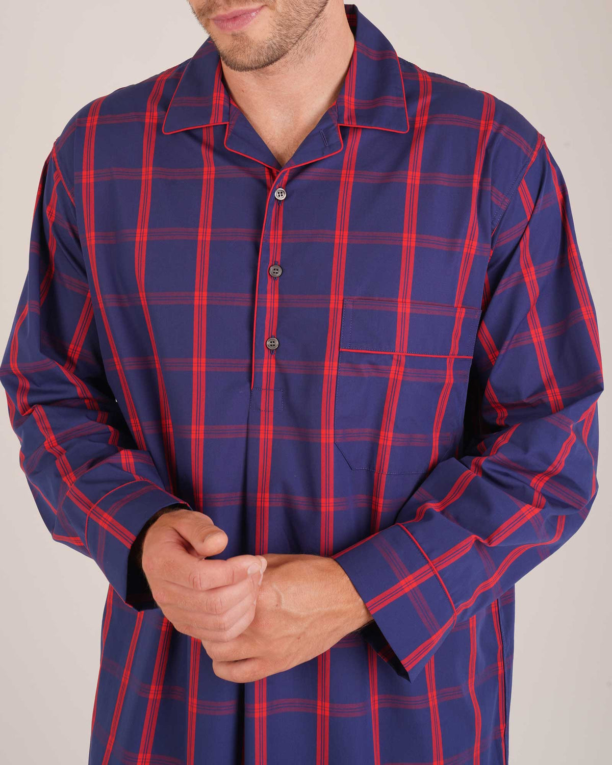 Bonsoir of London Men’s James Blue Red Tartan Classic Cotton Nightshirt, featuring a navy blue and red tartan check design, four-button placket, shirt-tail hem and generously cut fit, close up shot on a model.