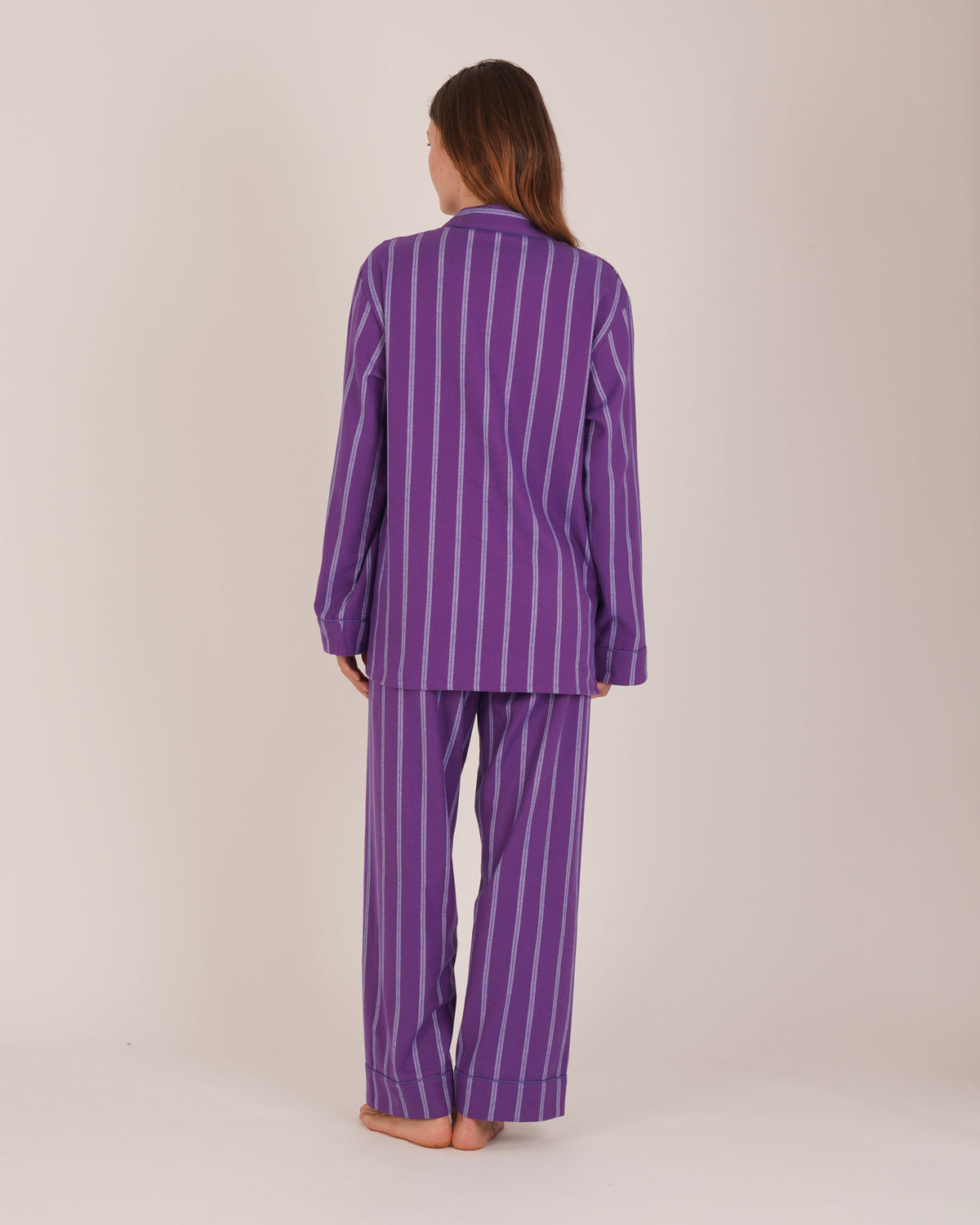 Bonsoir of London Women’s Lily Purple Stripe Brushed Cotton Pyjamas, featuring a purple striped design, square-hemmed jacket, half-elasticated waist with self-fabric tie trouser, complementary piping, full body shot on a model from the back.