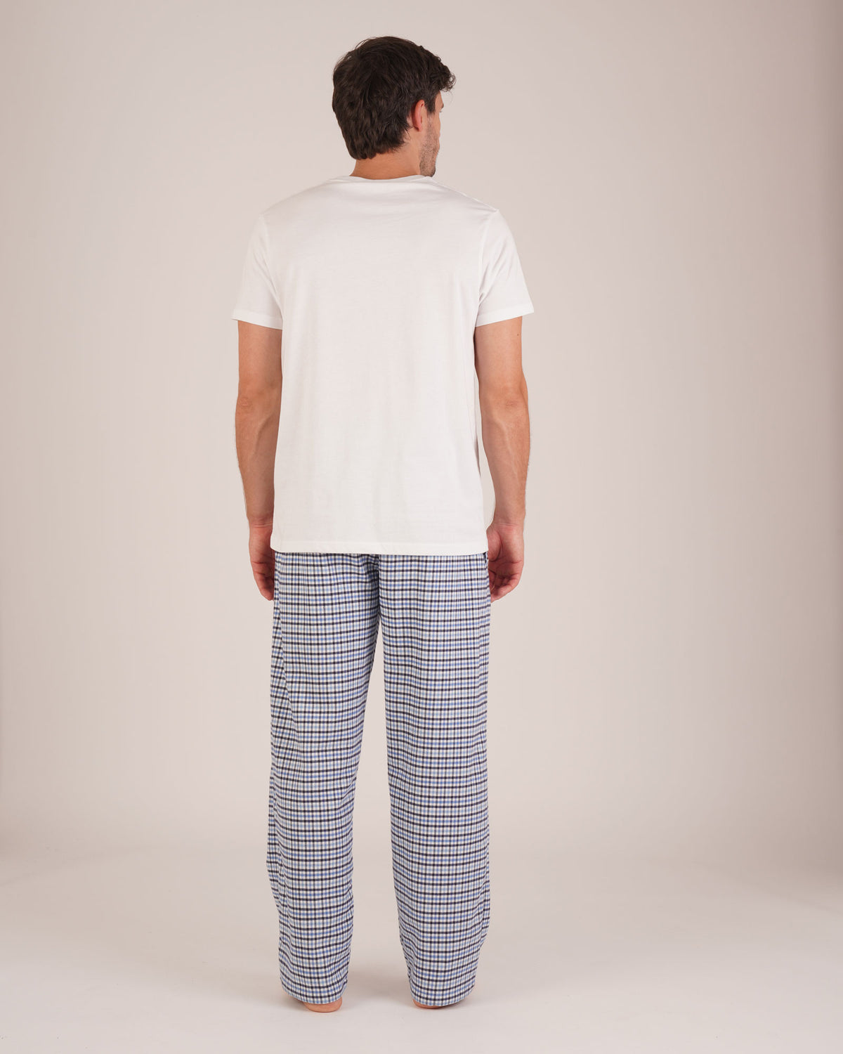 Bonsoir of London Men’s Arthur Blue Check Brushed Cotton Pyjama Trousers, featuring a blue, white and navy check design, 100% brushed cotton, fully elasticated waist, concealed button fly, self-fabric drawstring tie and pockets, full body shot on a model from the back.