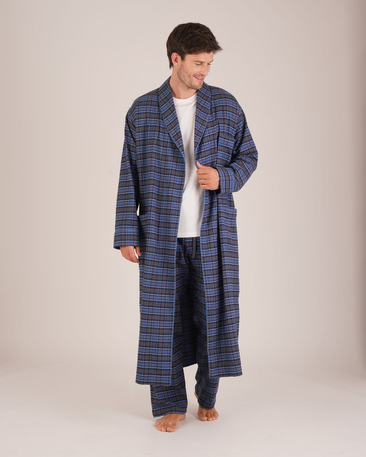 Bonsoir of London Men’s Theodore Blue Plaid Brushed Cotton Dressing Gown, featuring a blue and navy plaid design with subtle gold detailing, shawl collar, wide tie belt, patch pockets, full body shot on a model.