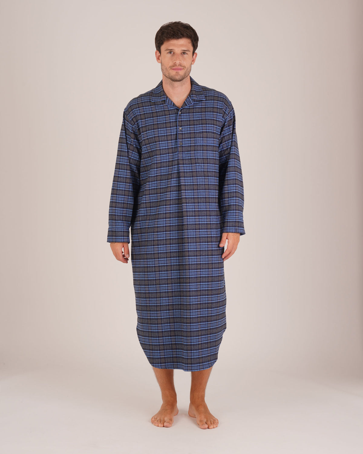 Bonsoir of London Men’s Theodore Blue Plaid Brushed Cotton Nightshirt, featuring a blue and navy plaid design with subtle gold detailing, four-button placket, shirt-tail hem and generously cut fit, full body shot on a model.