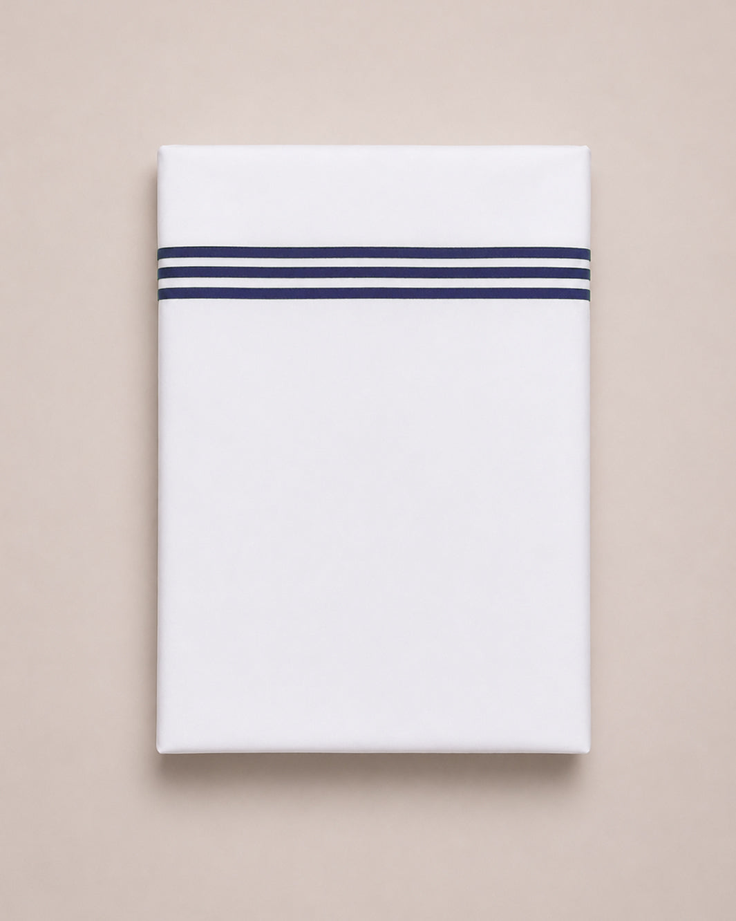 Bonsoir of London white cotton flat sheets with three navy embroidered stripes, folded on a studio background.