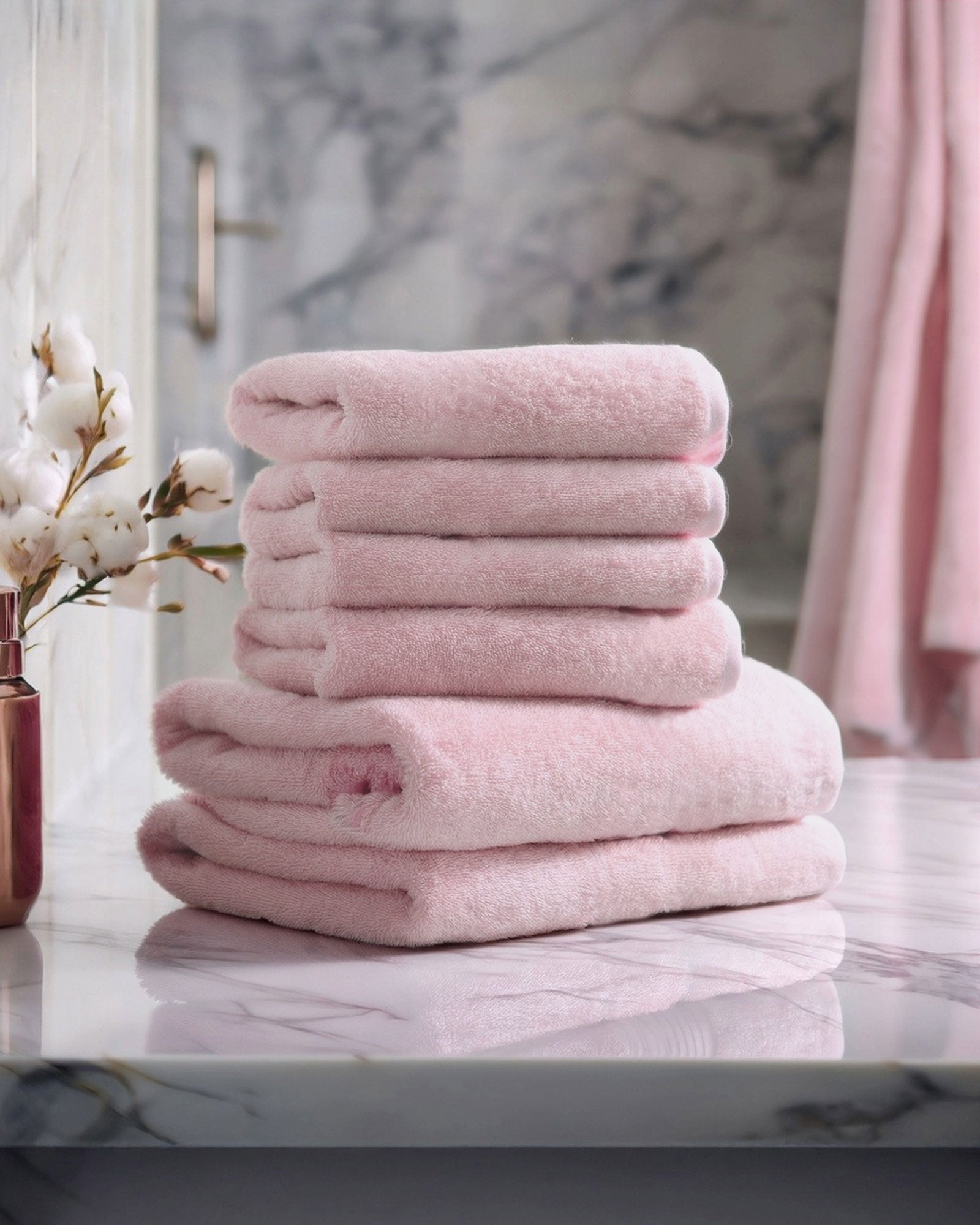 Stack of pink cotton towels on a marble surface with a blurred background