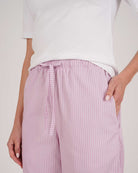 Bonsoir of London women's cotton long pyjama trousers in purple stripe print, elasticated and drawstring waist, close up shot on a model.