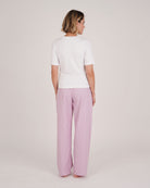 Bonsoir of London women's cotton long pyjama trousers in purple stripe print, elasticated and drawstring waist, full body shot from the back on a model.