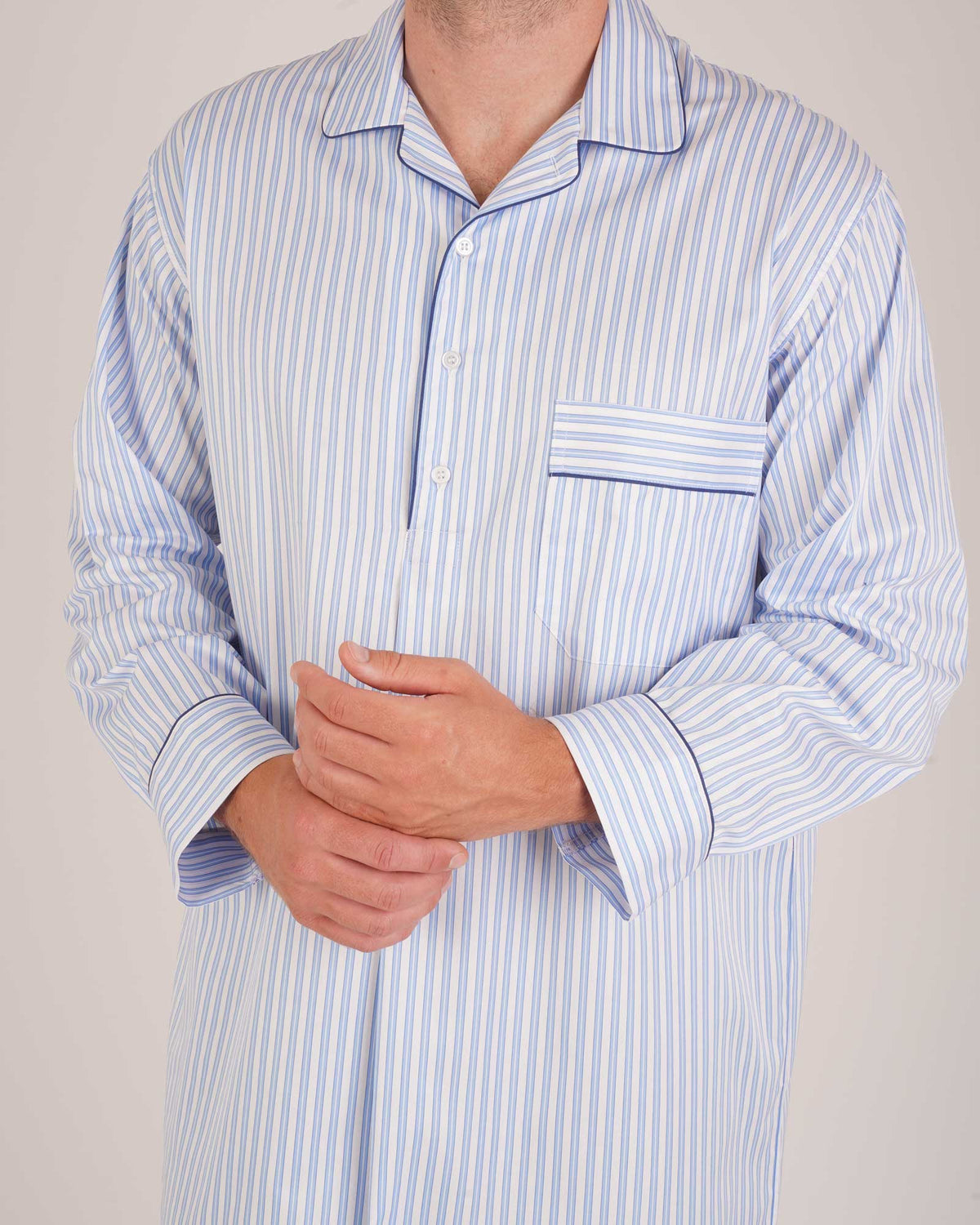 Bonsoir of London Men’s Charles Blue White Stripe Two-Fold Cotton Nightshirt, featuring a blue and white striped design, four-button placket, shirt-tail hem and generously cut fit, close up shot on a model.