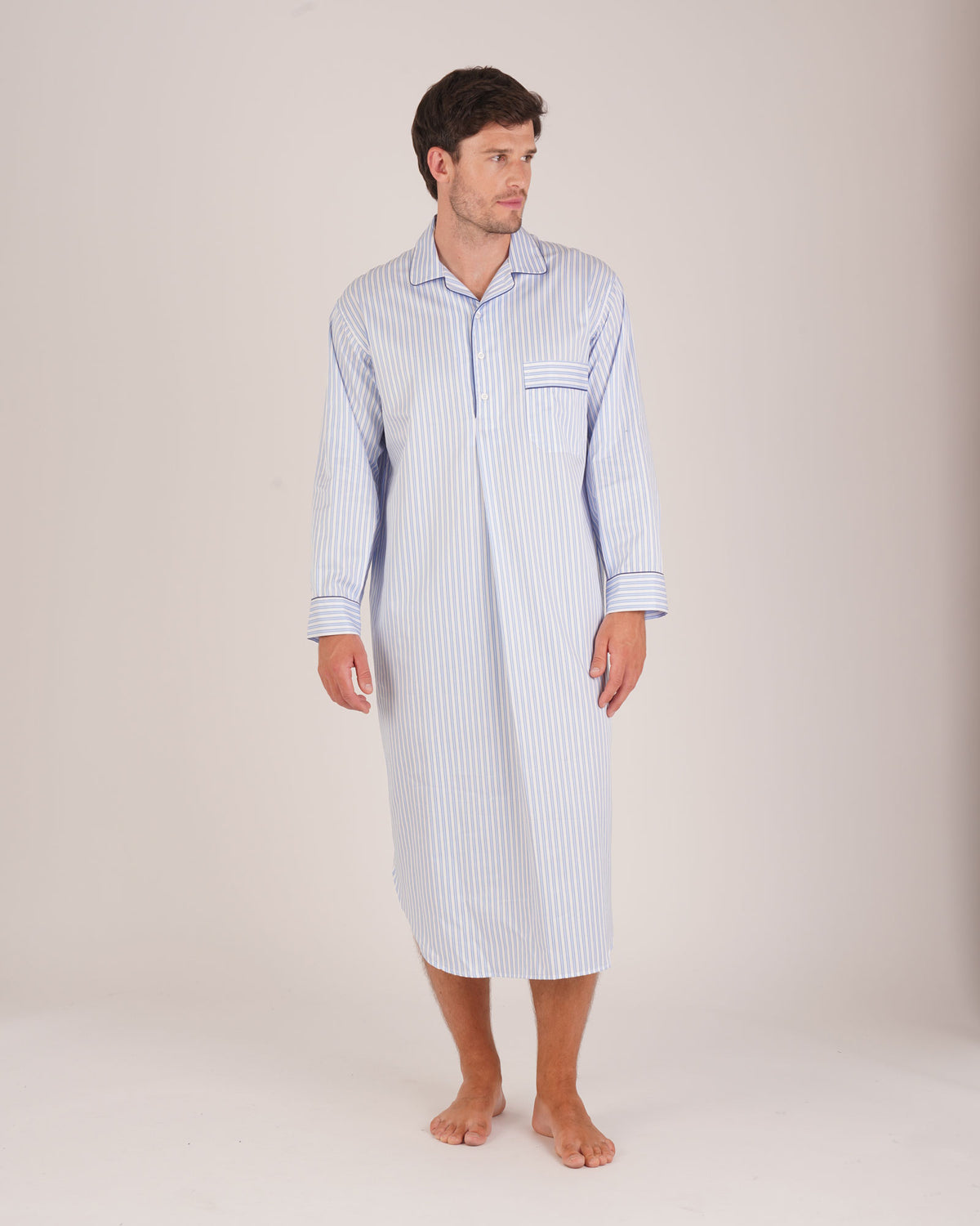 Bonsoir of London Men’s Charles Blue White Stripe Two-Fold Cotton Nightshirt, featuring a blue and white striped design, four-button placket, shirt-tail hem and generously cut fit, full body shot on a model.