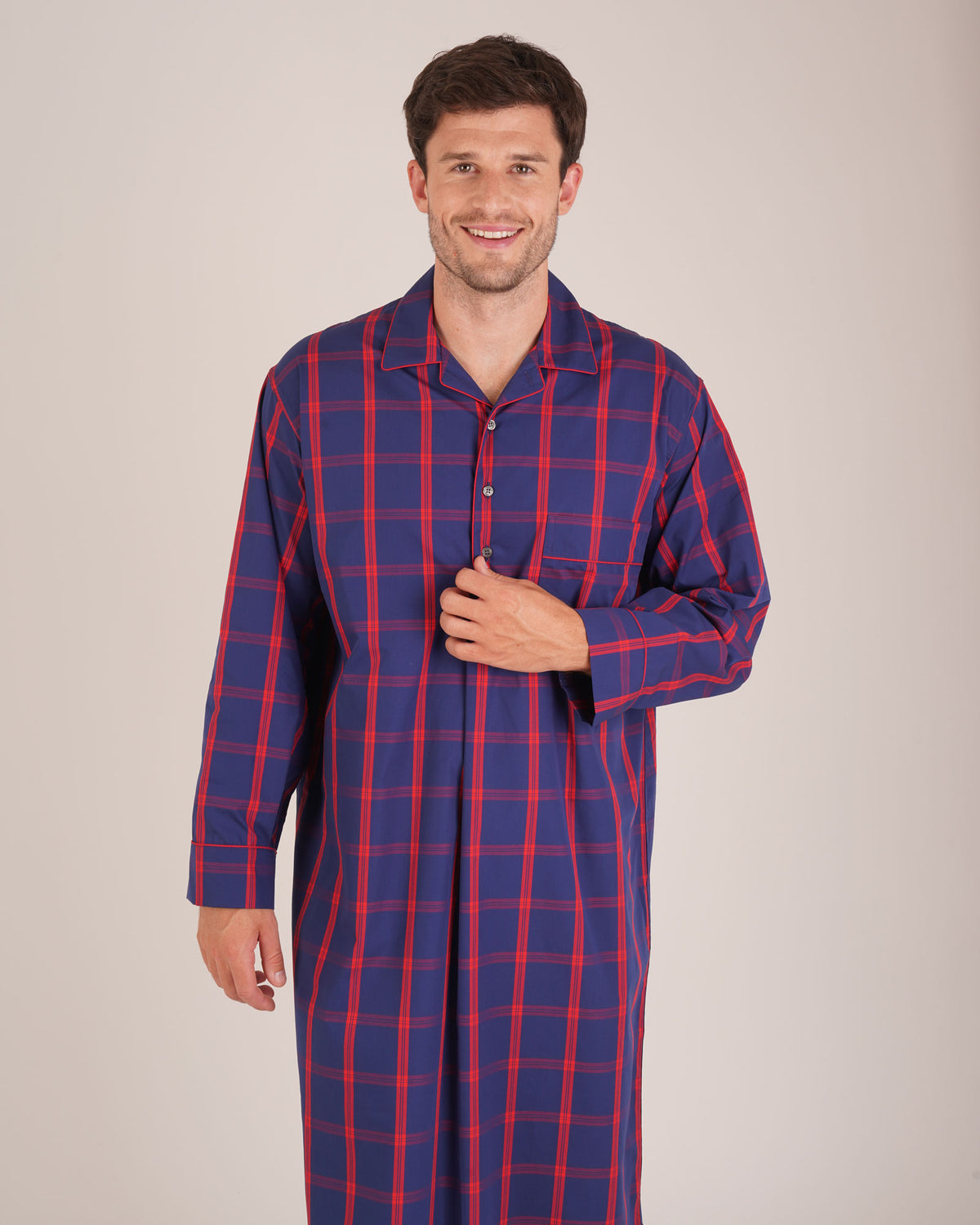 Bonsoir of London Men’s James Blue Red Tartan Classic Cotton Nightshirt, featuring a navy blue and red tartan check design, four-button placket, shirt-tail hem and generously cut fit, shot on a model.