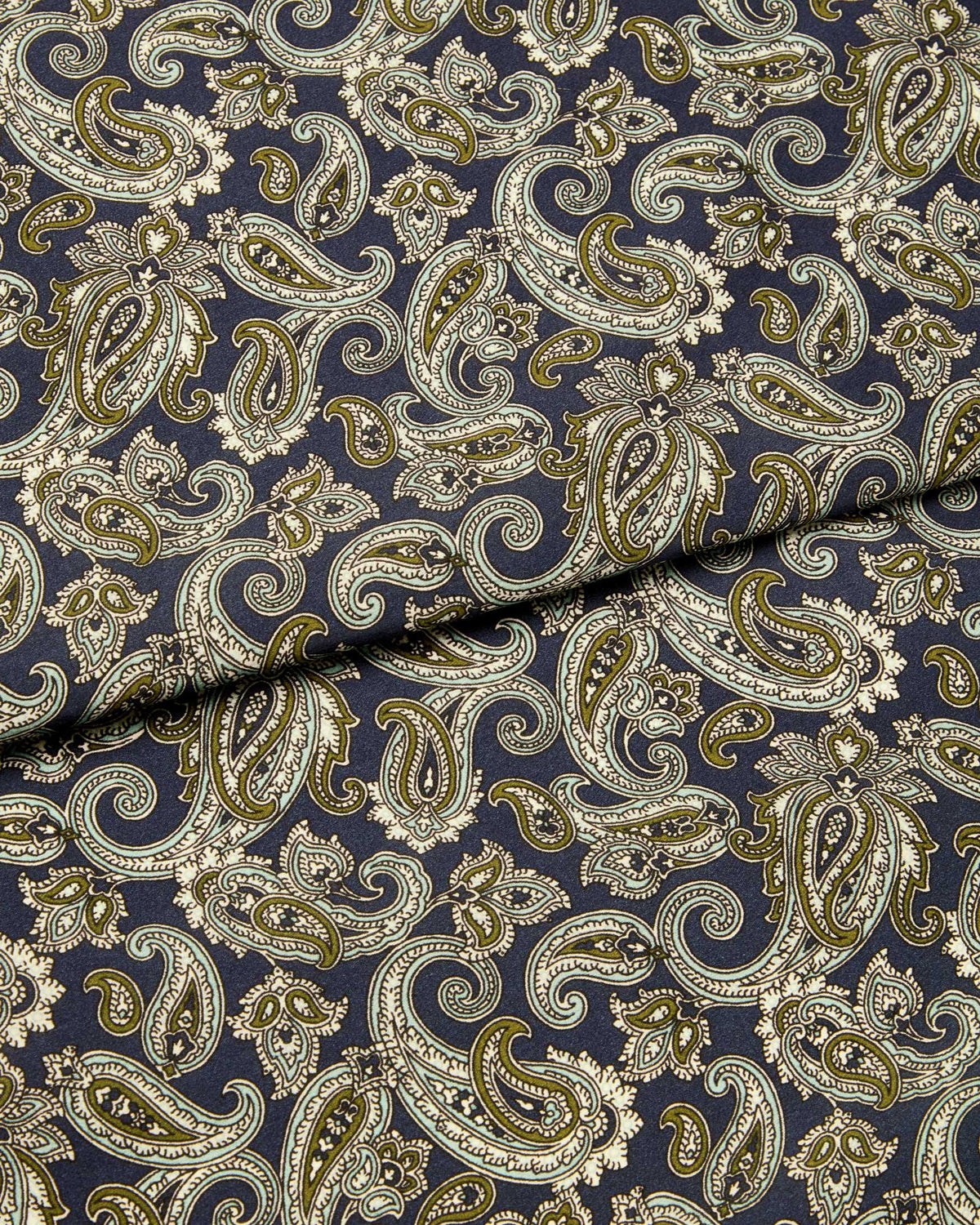 Bonsoir of London silk satin fabric, featuring a navy base with olive green, pale blue and cream paisley design, close up of the fabric.