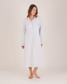 Bonsoir of London Women’s Isla Blue White Stripe Brushed Cotton Nightshirt, featuring a blue and white striped design, button placket, shirt-tail hem, piping detail, cuffs and breast pocket, full body shot on a model.