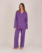 Bonsoir of London Women’s Lily Purple Stripe Brushed Cotton Pyjamas, featuring a purple striped design, square-hemmed jacket, half-elasticated waist with self-fabric tie trouser, complementary piping, full body shot on a model.