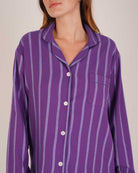 Bonsoir of London Women’s Lily Purple Stripe Brushed Cotton Pyjamas, featuring a purple striped design, square-hemmed jacket, half-elasticated waist with self-fabric tie trouser, complementary piping, close up shot on a model.