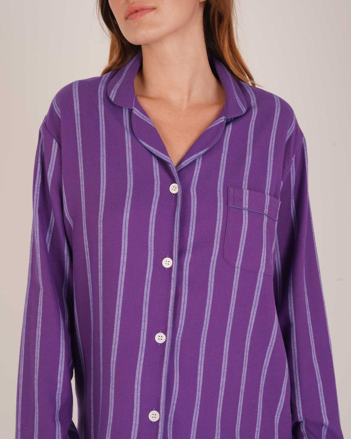 Bonsoir of London Women’s Lily Purple Stripe Brushed Cotton Pyjamas, featuring a purple striped design, square-hemmed jacket, half-elasticated waist with self-fabric tie trouser, complementary piping, close up shot on a model.