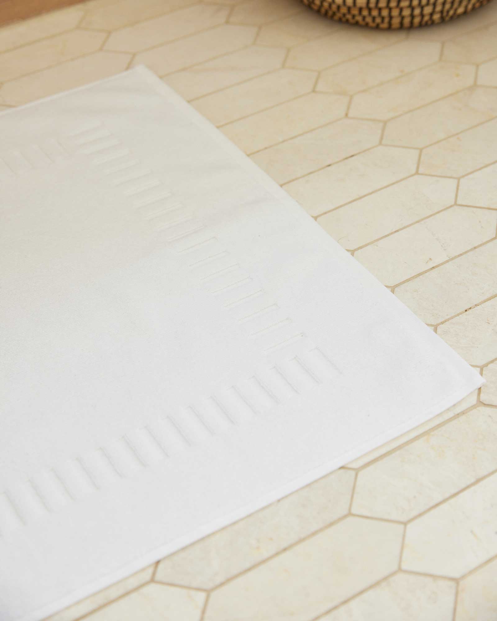 Bonsoir of London 100% Cotton Bathmat in white, detail close-up on a tile floor.