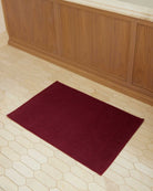 Bonsoir of London 100% Cotton Bathmat in red, full lifestyle shot on a tile floor.