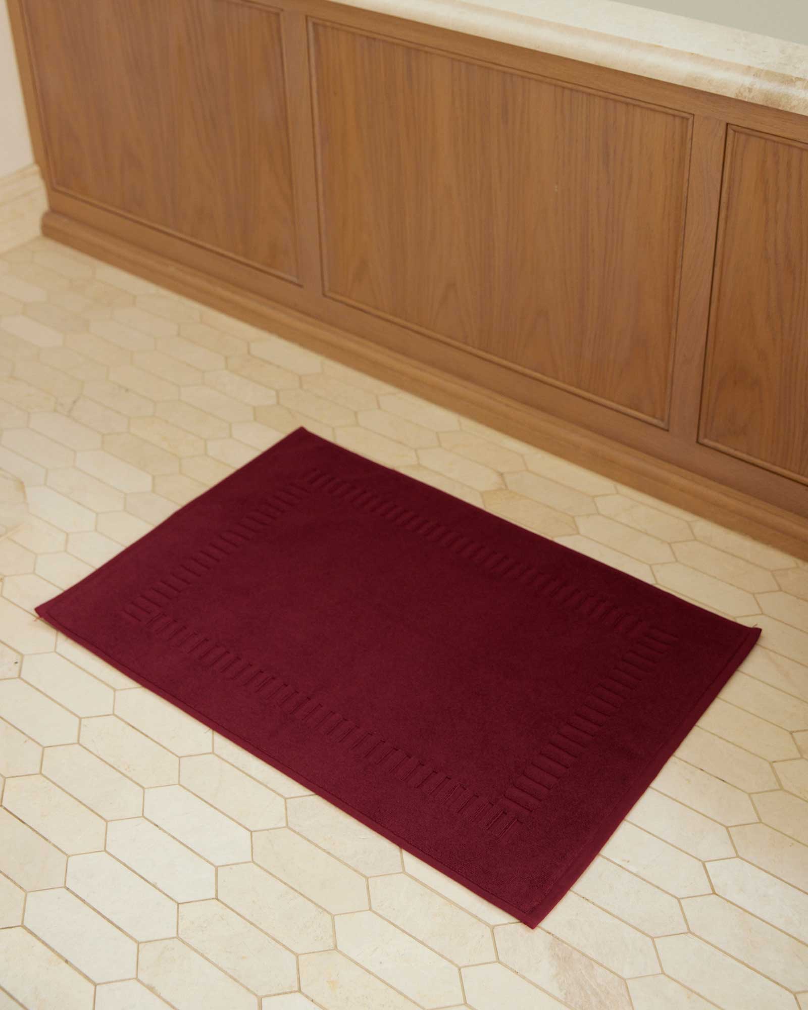 Bonsoir of London 100% Cotton Bathmat in red, full lifestyle shot on a tile floor.