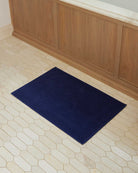 Bonsoir of London 100% Cotton Bathmat in navy, full lifestyle shot on a tile floor.