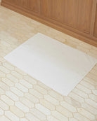 Bonsoir of London 100% Cotton Bathmat in white, lifestyle shot on a tile floor.