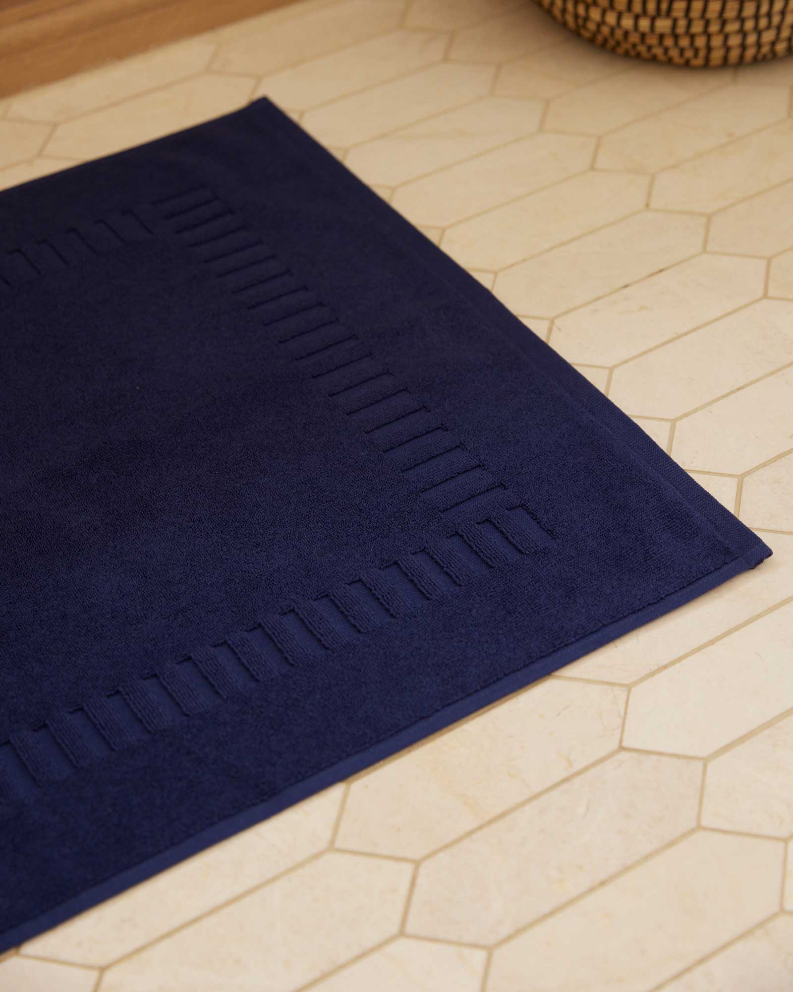 Bonsoir of London 100% Cotton bath mat in navy, detail close-up on a tile floor.