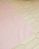 Bonsoir of London 100% Cotton Bathmat in pink, detail close-up on a beige tile floor.