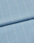 Close-up of light blue brushed cotton fabric with a subtle white check pattern