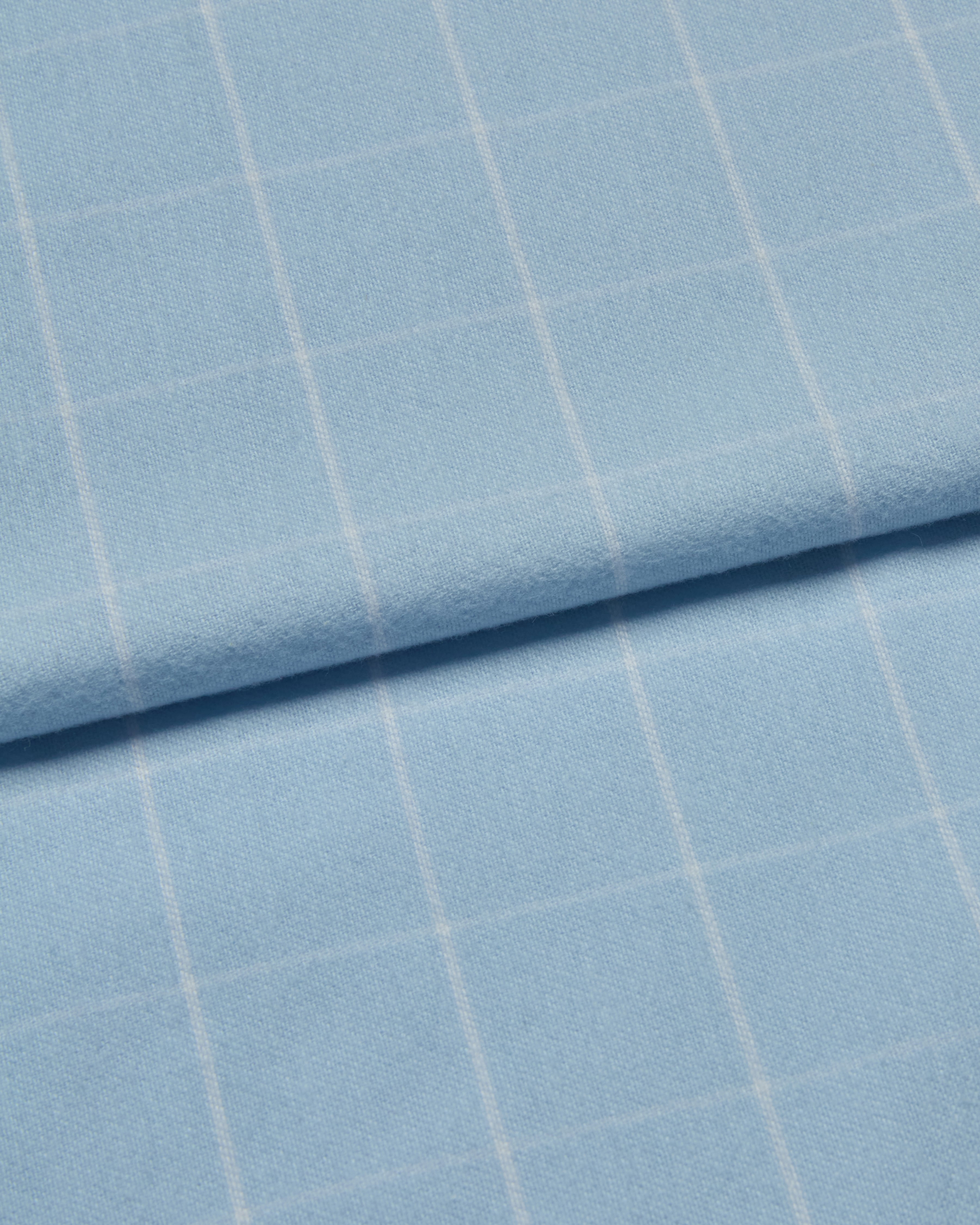 Close-up of light blue brushed cotton fabric with a subtle white check pattern