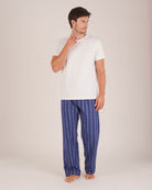 Bonsoir of London Men’s Alexander Navy White Stripe Brushed Cotton Pyjama Trousers, featuring a navy and white striped design, 100% brushed cotton, fully elasticated waist, concealed button fly, self-fabric drawstring tie and pockets, full body shot on a model.