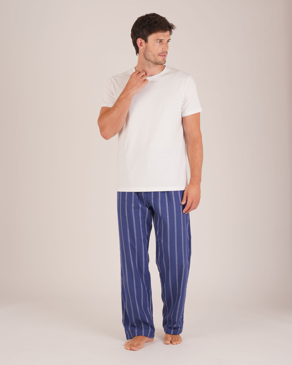 Bonsoir of London Men’s Alexander Navy White Stripe Brushed Cotton Pyjama Trousers, featuring a navy and white striped design, 100% brushed cotton, fully elasticated waist, concealed button fly, self-fabric drawstring tie and pockets, full body shot on a model.