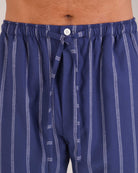Bonsoir of London Men’s Alexander Navy White Stripe Brushed Cotton Pyjama Trousers, featuring a navy and white striped design, 100% brushed cotton, fully elasticated waist, concealed button fly, self-fabric drawstring tie and pockets, close up shot on a model.