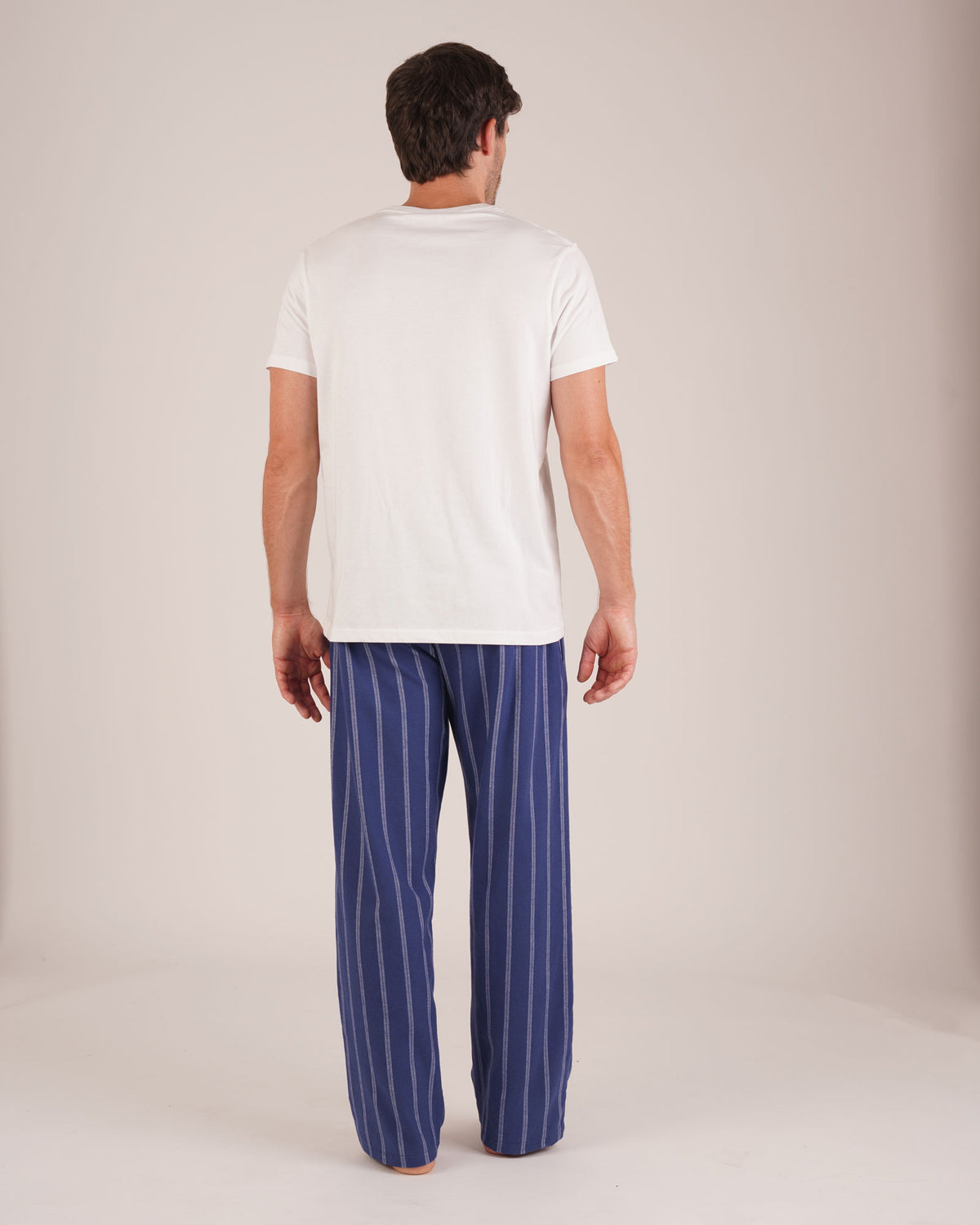 Bonsoir of London Men’s Alexander Navy White Stripe Brushed Cotton Pyjama Trousers, featuring a navy and white striped design, 100% brushed cotton, fully elasticated waist, concealed button fly, self-fabric drawstring tie and pockets, full body shot on a model from the back.