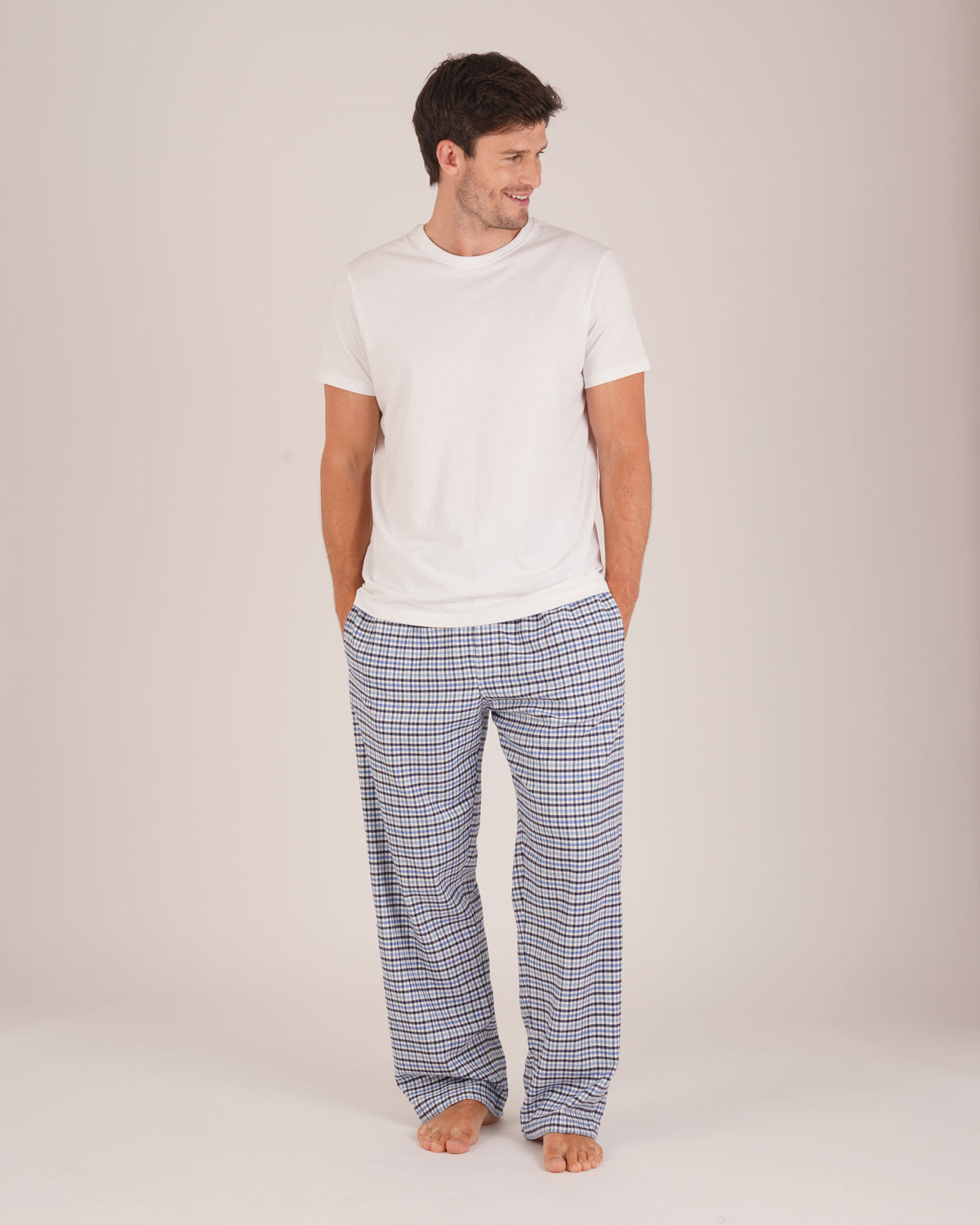 Bonsoir of London Men’s Arthur Blue Check Brushed Cotton Pyjama Trousers, featuring a blue, pale blue, white and navy check design, 100% brushed cotton, fully elasticated waist, concealed button fly, self-fabric drawstring tie and pockets, full body shot on a model.
