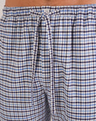 Bonsoir of London Men’s Arthur Blue Check Brushed Cotton Pyjama Trousers, featuring a blue, white and navy check design, 100% brushed cotton, fully elasticated waist, concealed button fly, self-fabric drawstring tie and pockets, close up shot on a model.