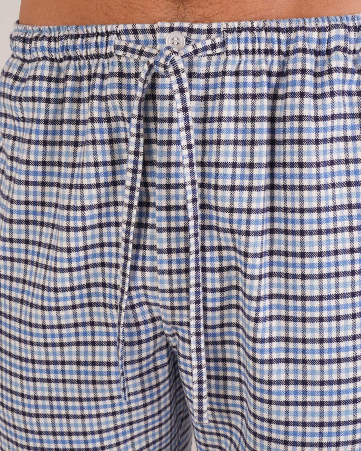 Bonsoir of London Men’s Arthur Blue Check Brushed Cotton Pyjama Trousers, featuring a blue, white and navy check design, 100% brushed cotton, fully elasticated waist, concealed button fly, self-fabric drawstring tie and pockets, close up shot on a model.