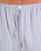 Bonsoir of London Men’s Oliver Blue White Stripe Brushed Cotton Pyjama Trousers, featuring a pale blue and white striped design, 100% brushed cotton, fully elasticated waist, concealed button fly, self-fabric drawstring tie and pockets, close up shot on a model.