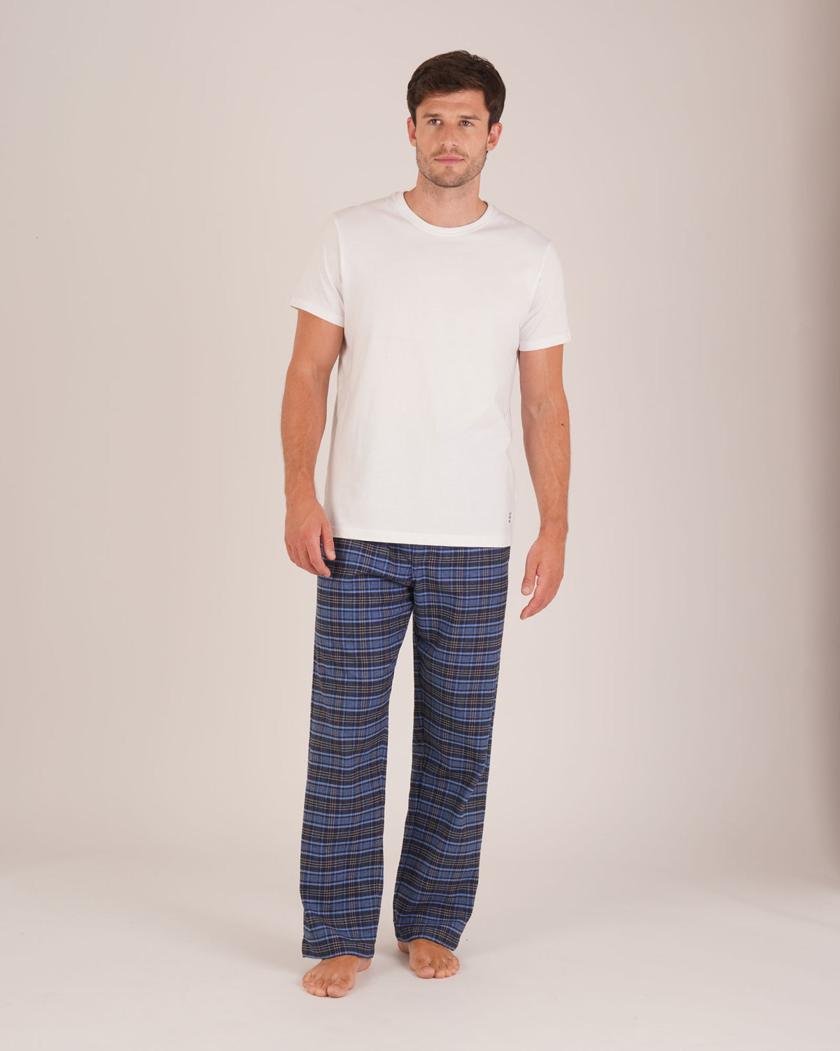 Bonsoir of London Men’s Theodore Blue Plaid Brushed Cotton Pyjama Trousers, featuring a blue and navy plaid design, 100% brushed cotton, fully elasticated waist, concealed button fly, self-fabric drawstring tie and pockets, full body shot on a model.