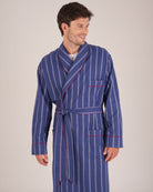 Bonsoir of London Men’s Alexander Navy White Stripe Brushed Cotton Dressing Gown, featuring 100% brushed cotton, a navy and white striped design, shawl collar, wide tie belt and patch pockets, half body shot on a model.