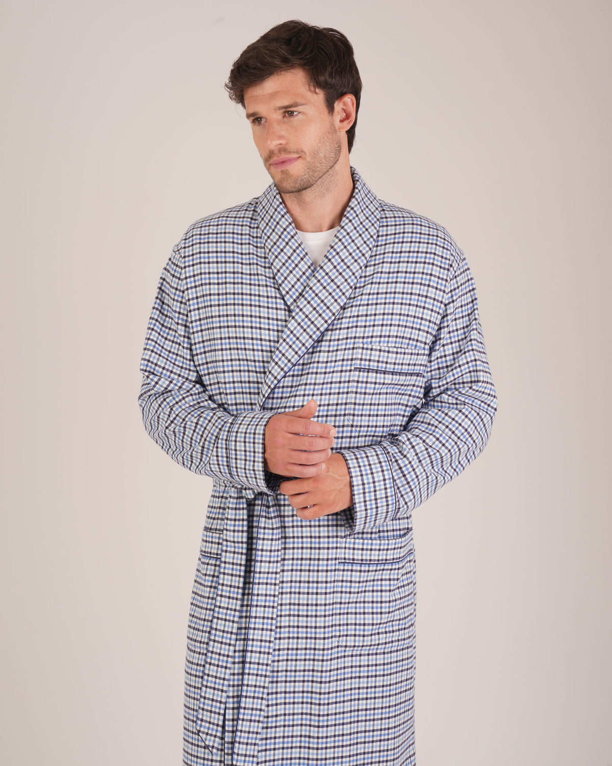 Bonsoir of London Men’s Arthur Blue Check Brushed Cotton Dressing Gown, featuring a soft blue, white and navy check design, shawl collar, wide tie belt, patch pockets, half body shot on a model.