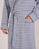 Bonsoir of London Men’s Arthur Blue Check Brushed Cotton Dressing Gown, featuring a soft blue, white and navy check design, shawl collar, wide tie belt, patch pockets, close up shot on a model.