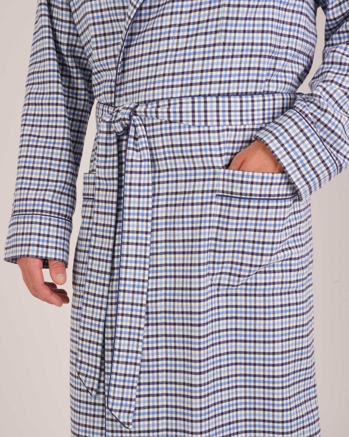 Bonsoir of London Men’s Arthur Blue Check Brushed Cotton Dressing Gown, featuring a soft blue, white and navy check design, shawl collar, wide tie belt, patch pockets, close up shot on a model.