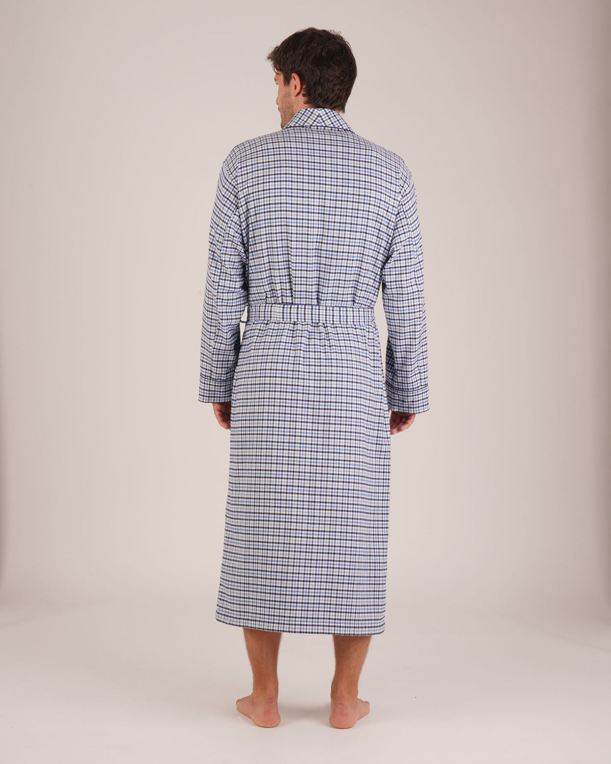 Bonsoir of London Men’s Arthur Blue Check Brushed Cotton Dressing Gown, featuring a soft blue, white and navy check design, shawl collar, wide tie belt, patch pockets, full body shot on a model from the back.