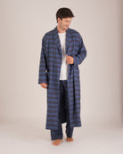 Bonsoir of London Men’s Theodore Blue Plaid Brushed Cotton Dressing Gown, featuring a blue and navy plaid design with subtle gold detailing, shawl collar, wide tie belt, patch pockets, full body shot on a model.