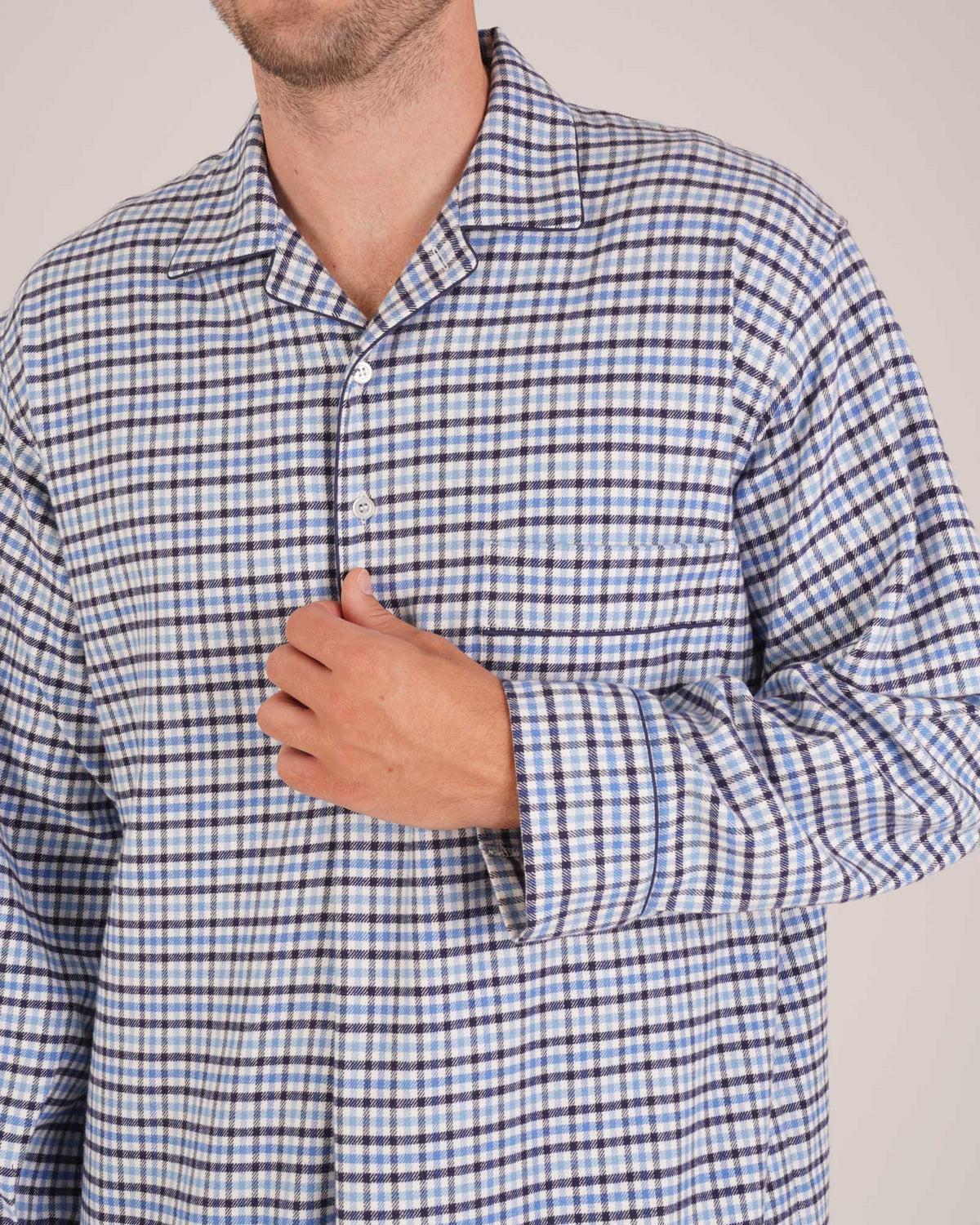 Bonsoir of London Men’s Arthur Blue Check Brushed Cotton Nightshirt, featuring a blue, white and navy check design, four-button placket, shirt-tail hem and generously cut fit, close up shot on a model.