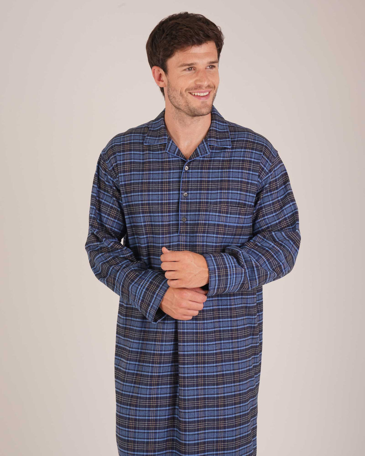Bonsoir of London Men’s Theodore Blue Plaid Brushed Cotton Nightshirt, featuring a blue and navy plaid design with subtle gold detailing, four-button placket, shirt-tail hem and generously cut fit, shot on a model.