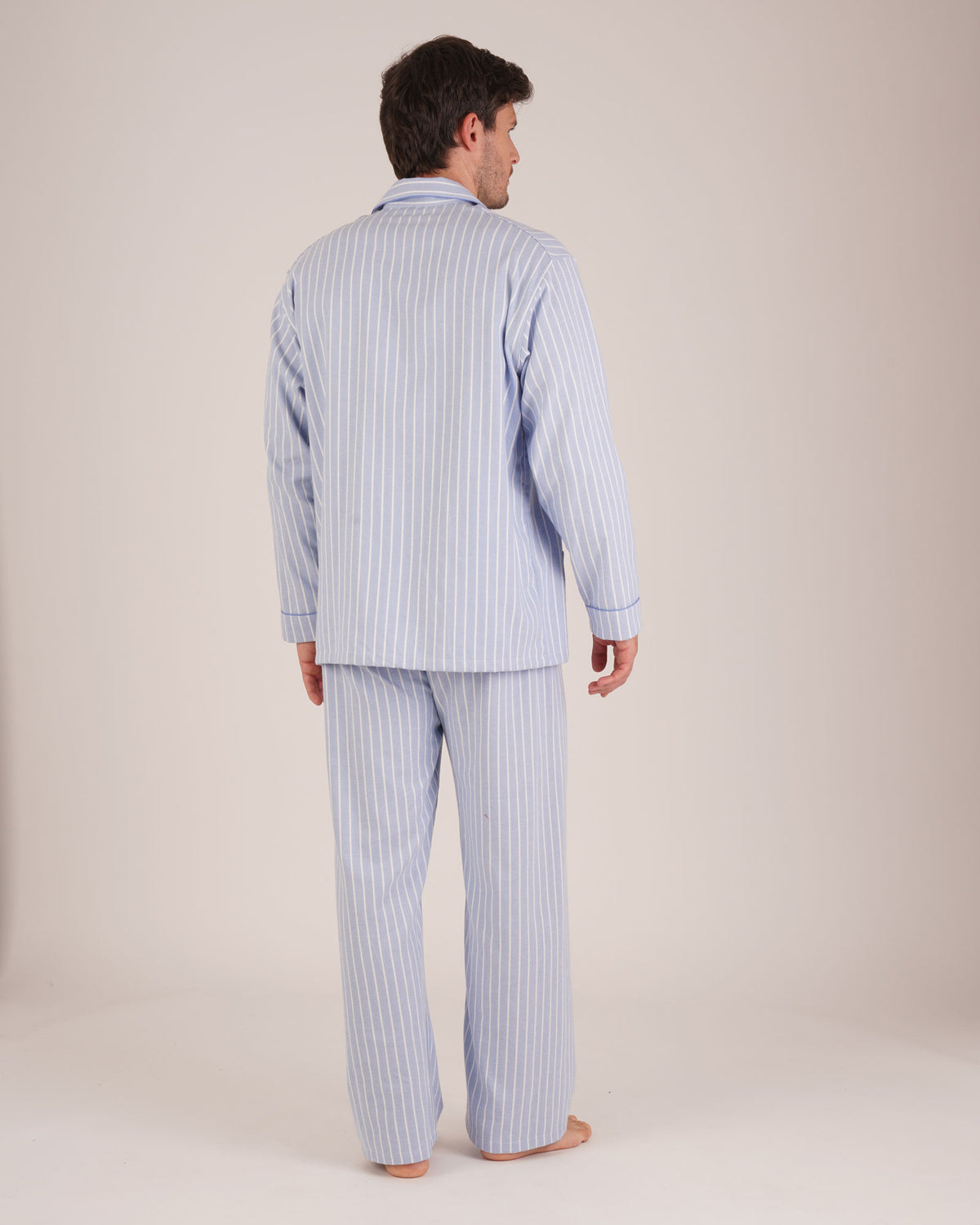 Bonsoir of London Men’s Oliver Blue White Stripe Brushed Cotton Pyjamas, featuring a pale blue and white striped design, three jacket pockets, elasticated-waist trousers, button fastening and concealed button fly, full body shot on a model from the back.