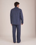 Bonsoir of London Men’s Theodore Blue Plaid Brushed Cotton Pyjamas, featuring a blue and navy plaid design with subtle gold detailing, three jacket pockets, elasticated-waist trousers, button fastening and concealed button fly, full body shot on a model from the back.