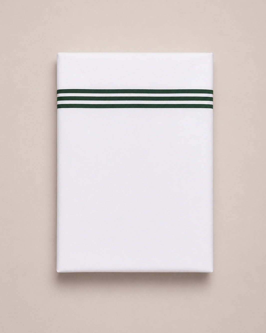 Bonsoir of London white cotton flat sheets with three green embroidered stripes, folded on a studio background.