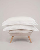 Bonsoir of London 100% Cotton Oxford Pillowcases White, set of 2 on a fabric stool shot in a studio.