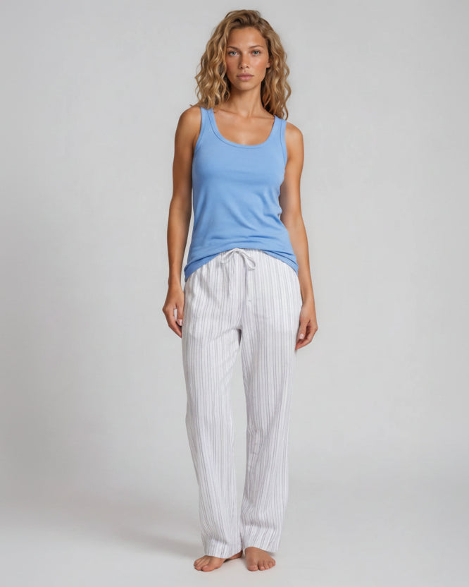 Woman wearing a blue tank top and white striped pajama pants on a gray Bonsoir of London 