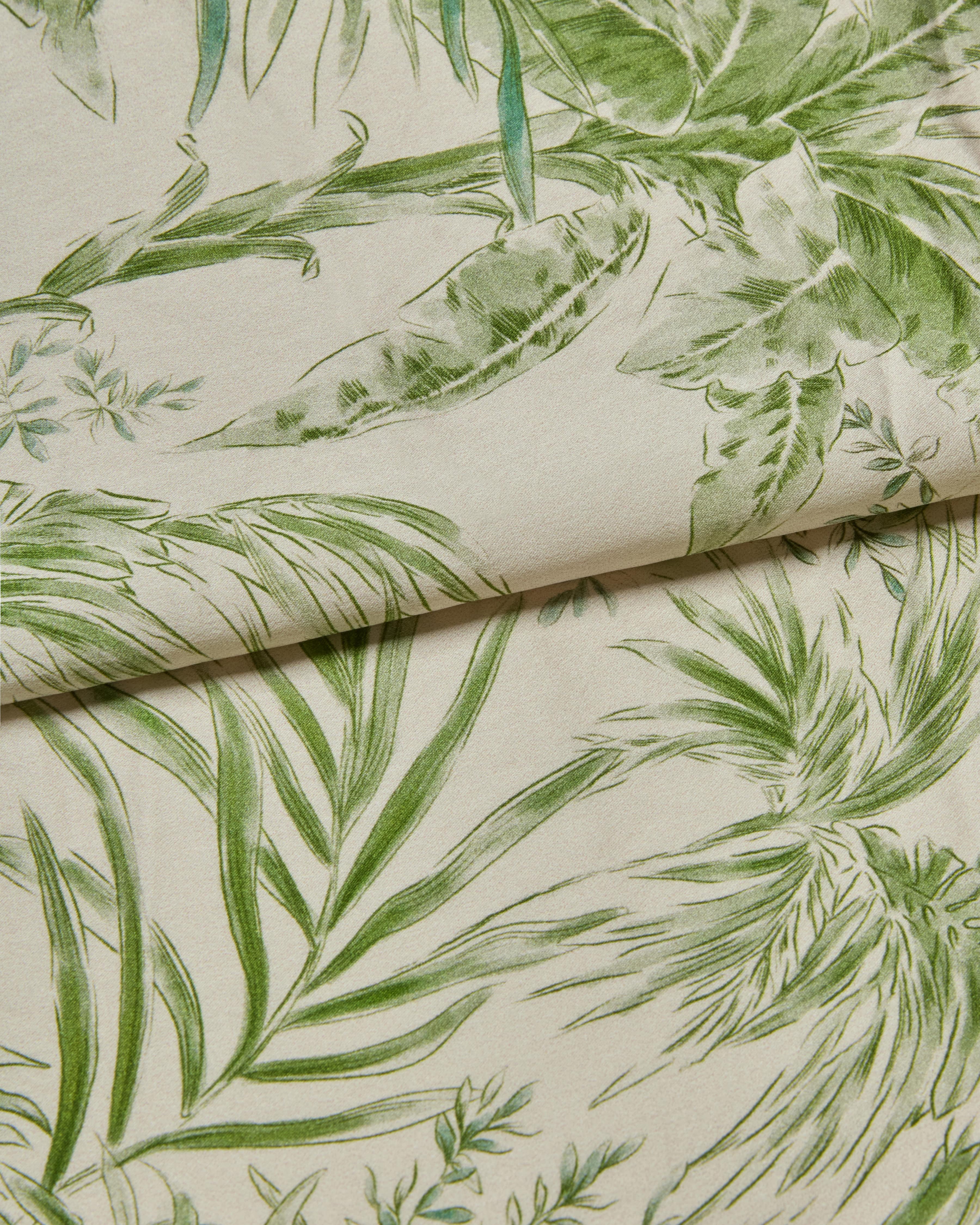 Silk Fabric close-up with green leaf pattern on a cream background
