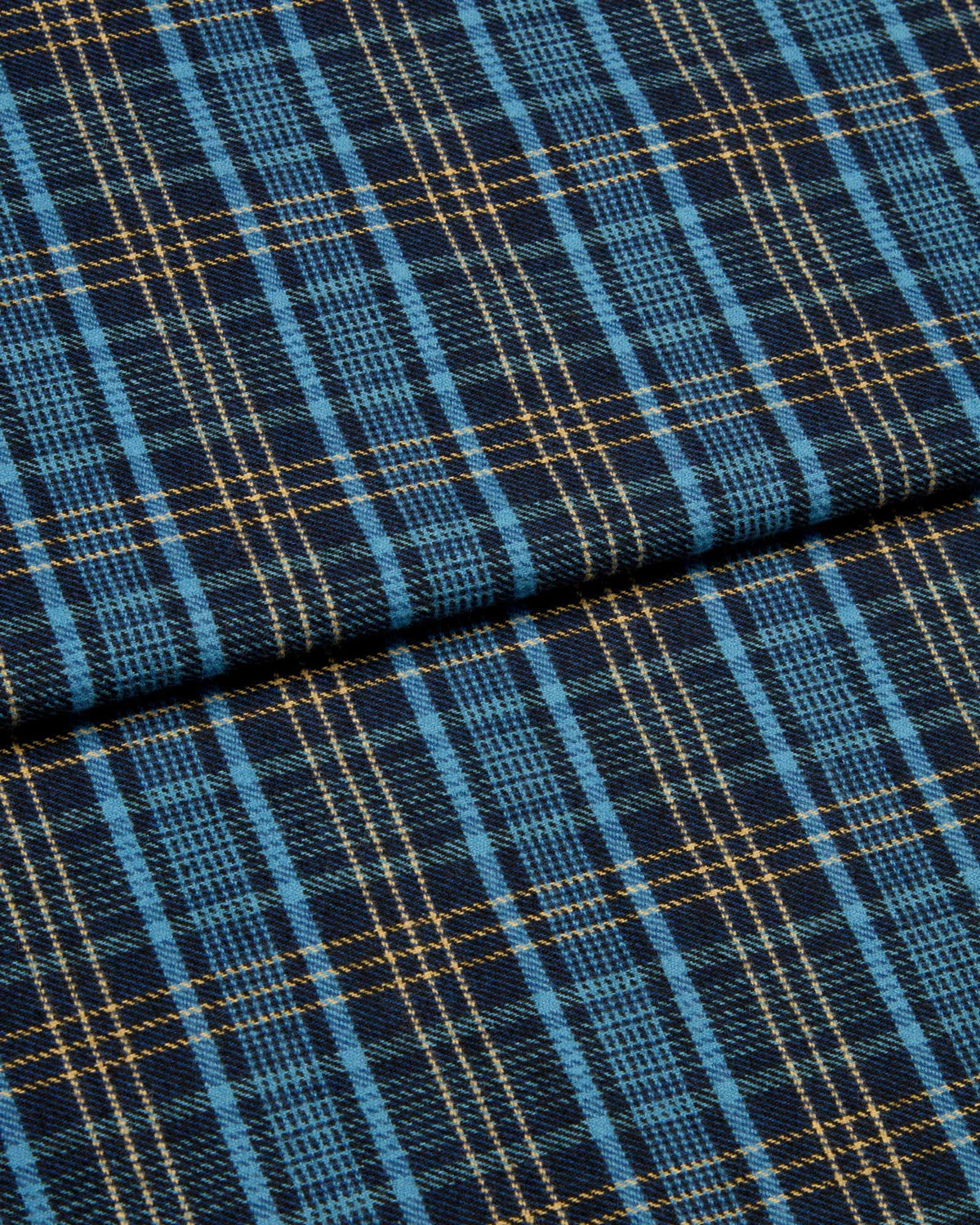Bonsoir of London brushed cotton fabric, featuring a blue and navy plaid design with subtle gold detailing, close up of the fabric.